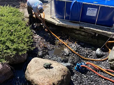 Person cleaning pond near temporary pool setup.