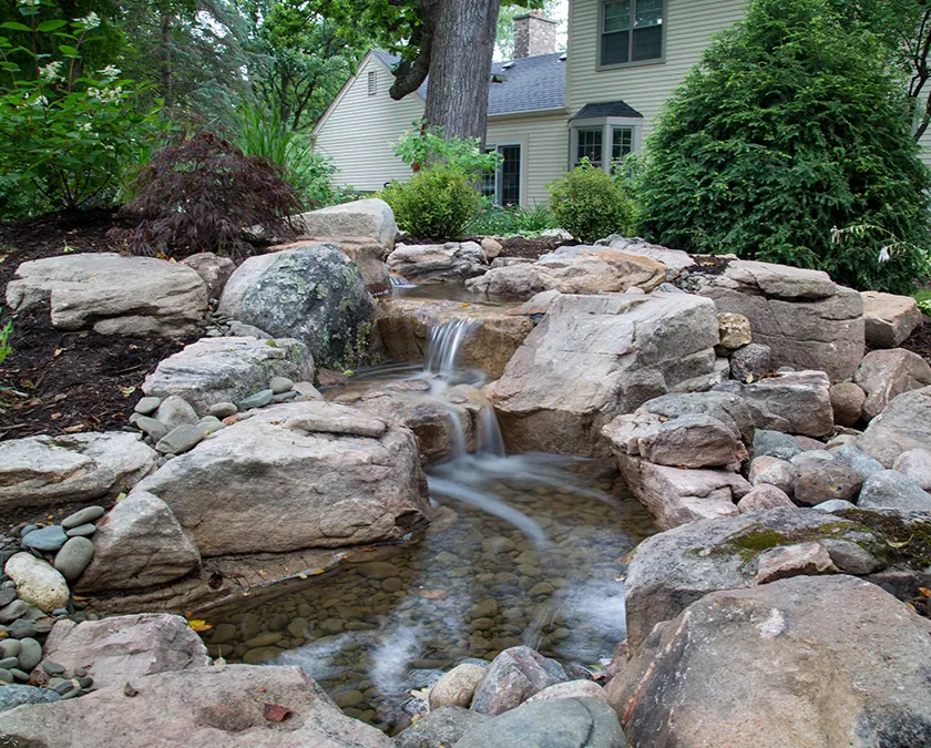 Backyard garden with small waterfall and stones.