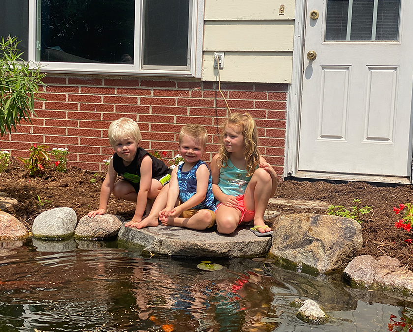 Children sitting by garden pond.