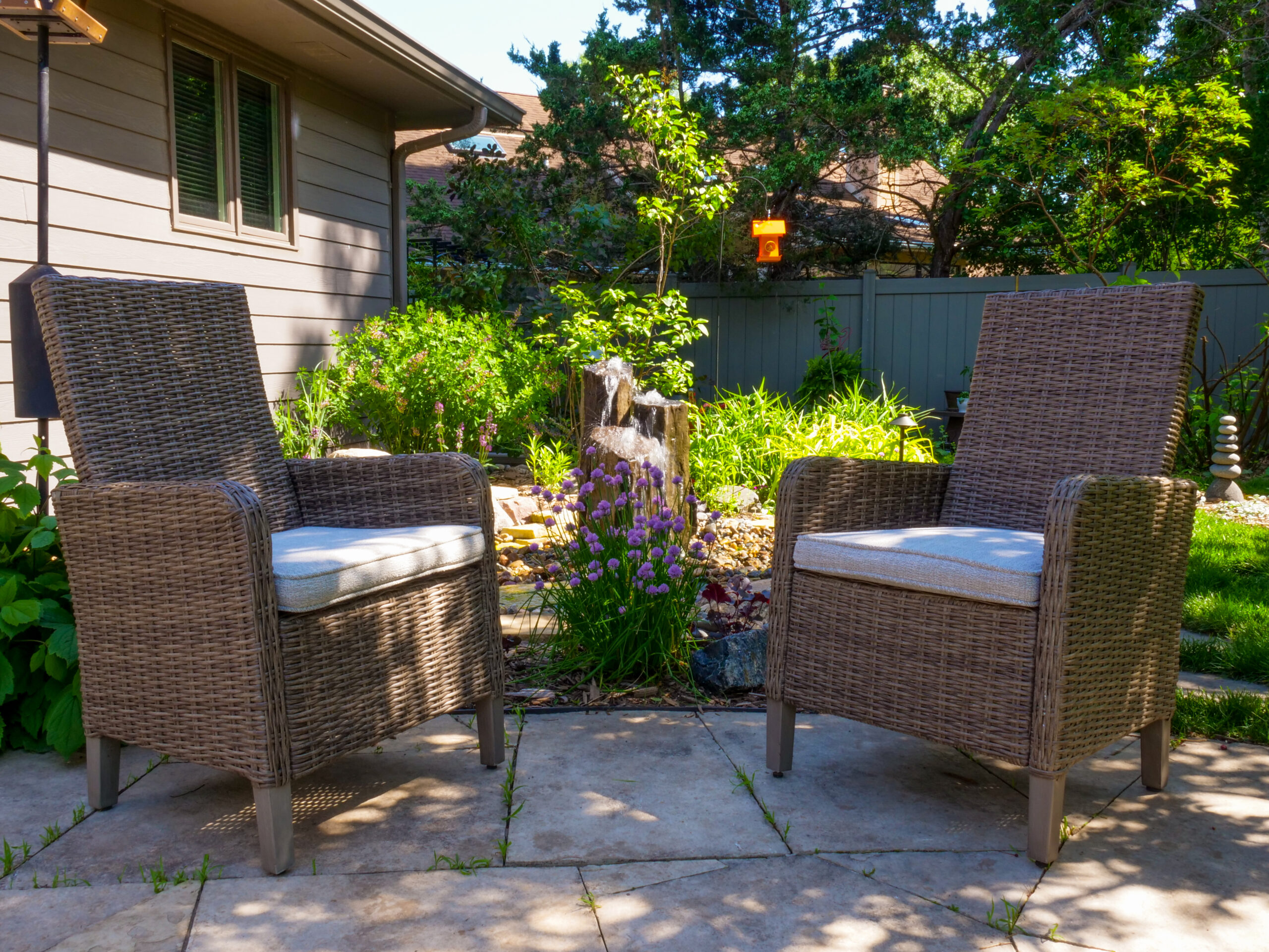 Two wicker chairs in a sunny garden.